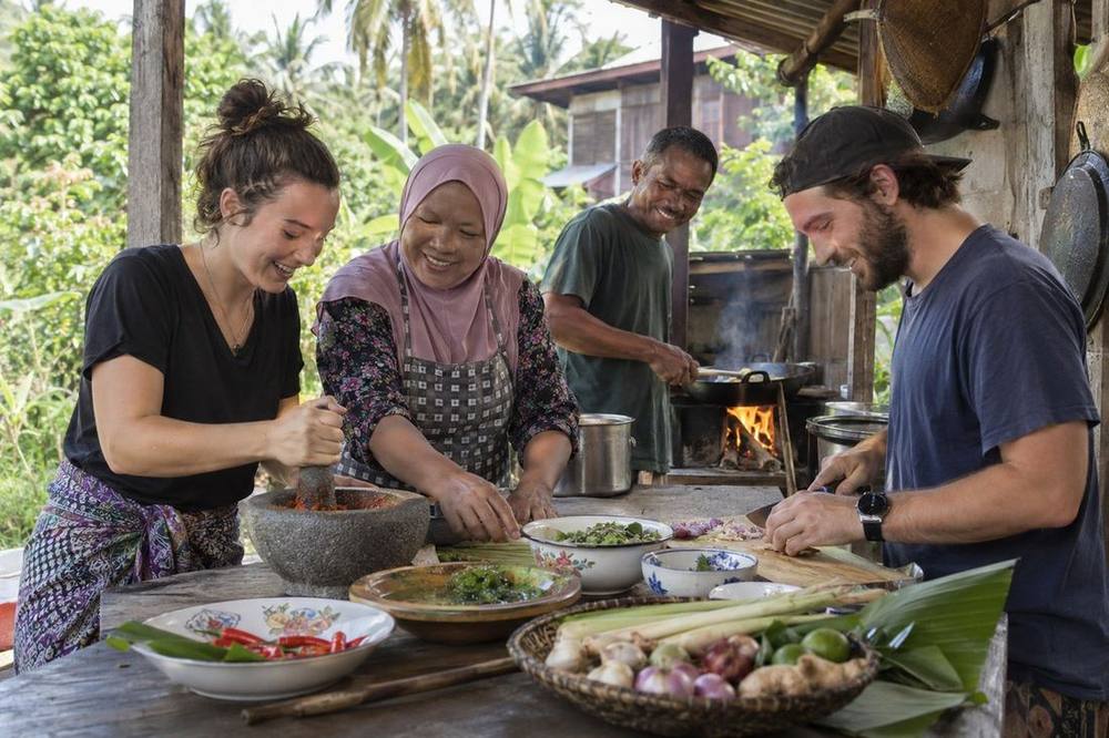 Guests learning to cook Malaysian food with a host family at a village homestay