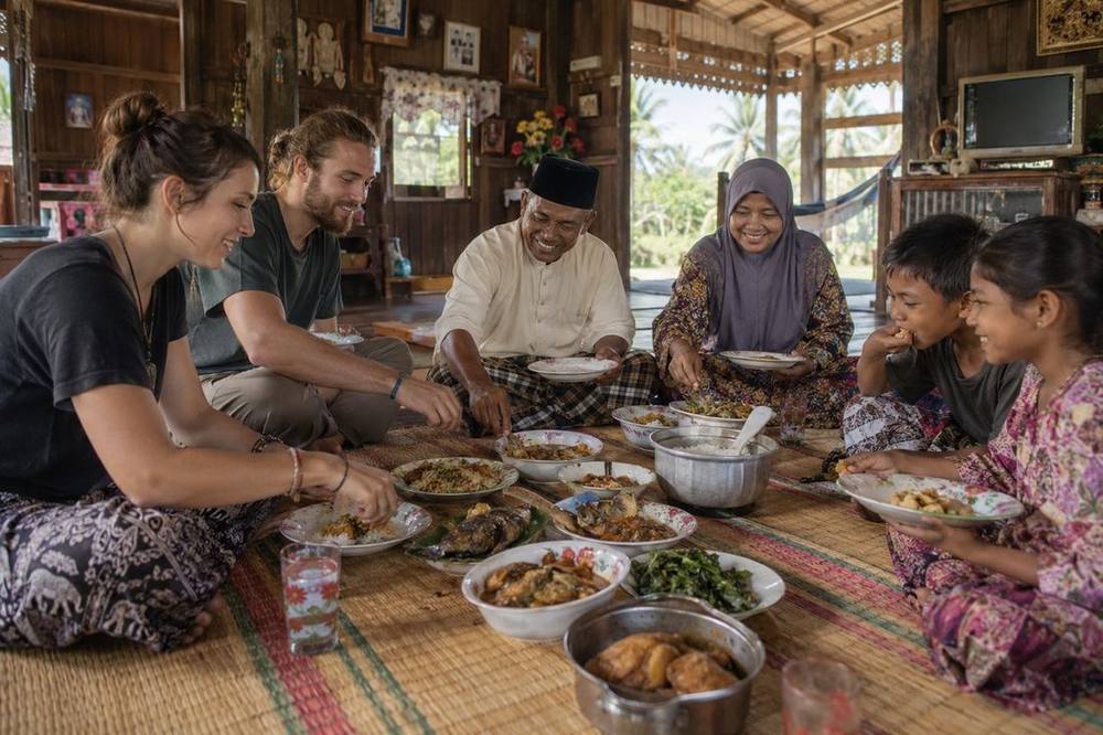 Travellers sharing a home-cooked meal with a host family at a homestay